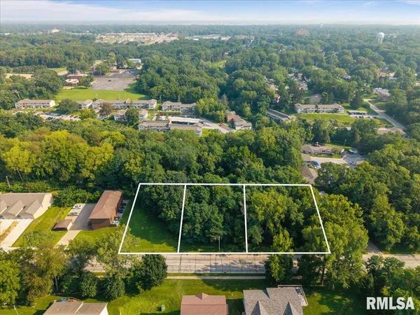 an aerial view of residential houses with outdoor space and trees