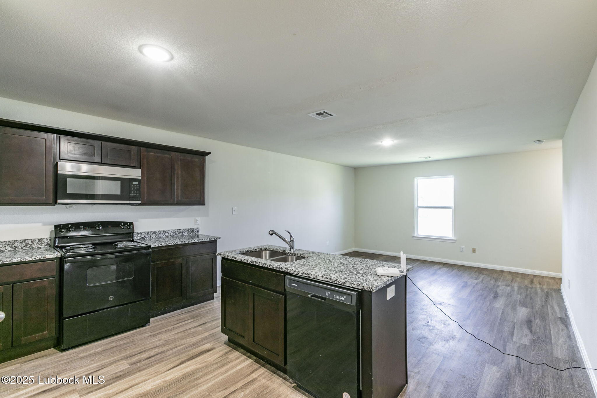 1714 East Cornell Street Lubbock, TX 79403 - Photo 5 of 18 a kitchen with stainless steel appliances granite countertop a stove a sink and a microwave