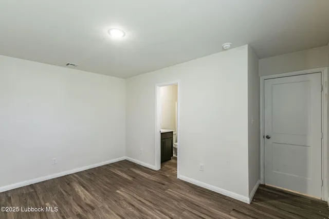 a view of an empty room with wooden floor and closet
