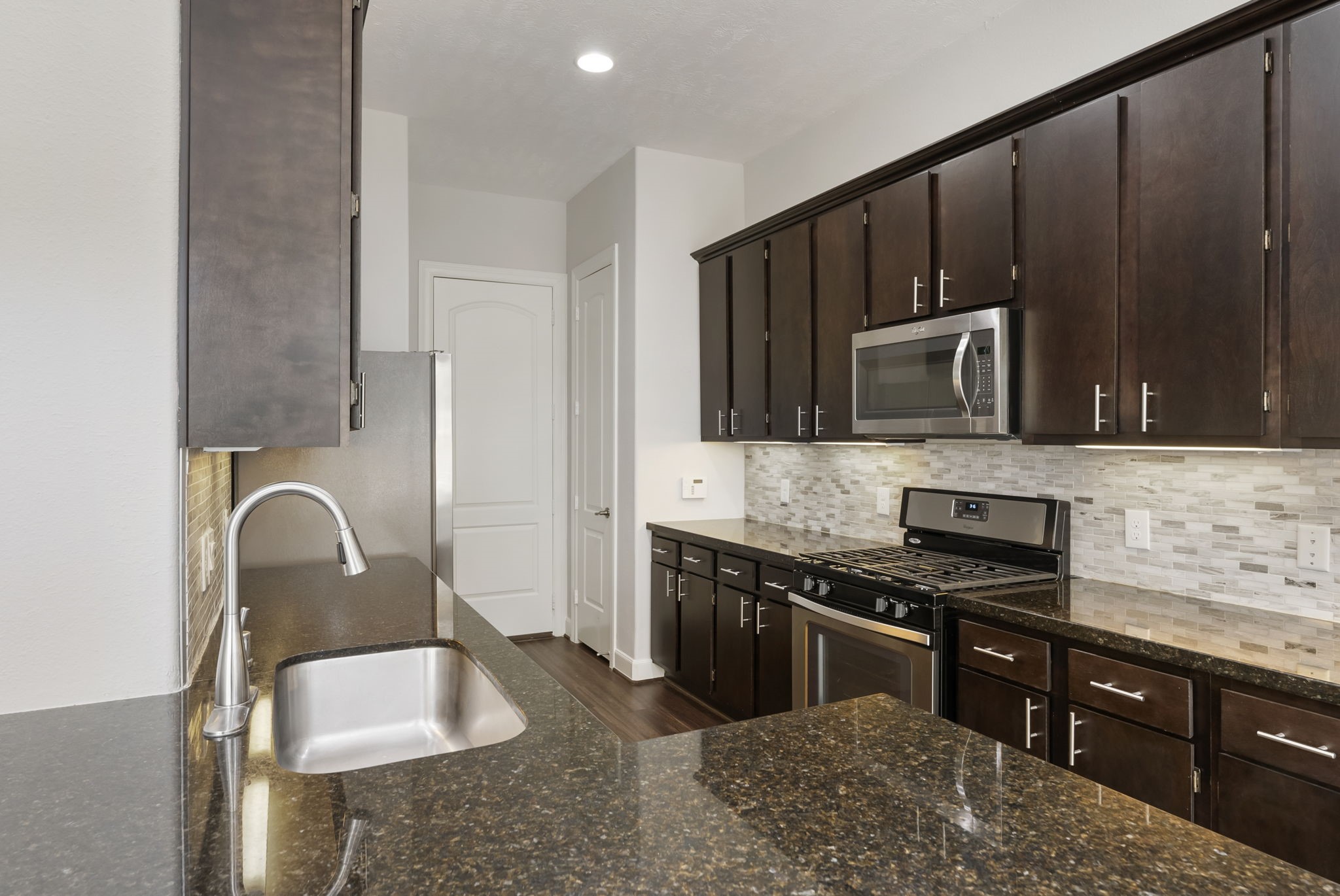 31 Aventura Place Spring, TX 77389 - Photo 18 of 49 a kitchen with granite countertop a stove a sink and a microwave