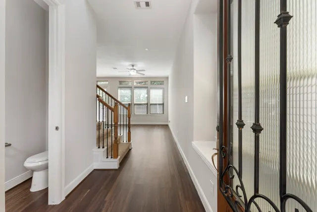a view of an empty room with wooden floor and a ceiling fan