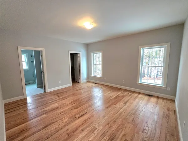 an empty room with wooden floor and windows