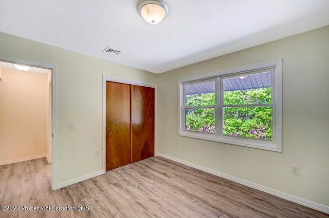 a view of empty room with wooden floor and fan