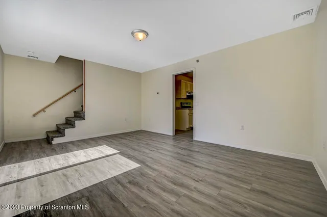 a view of an empty room with wooden floor and stairs
