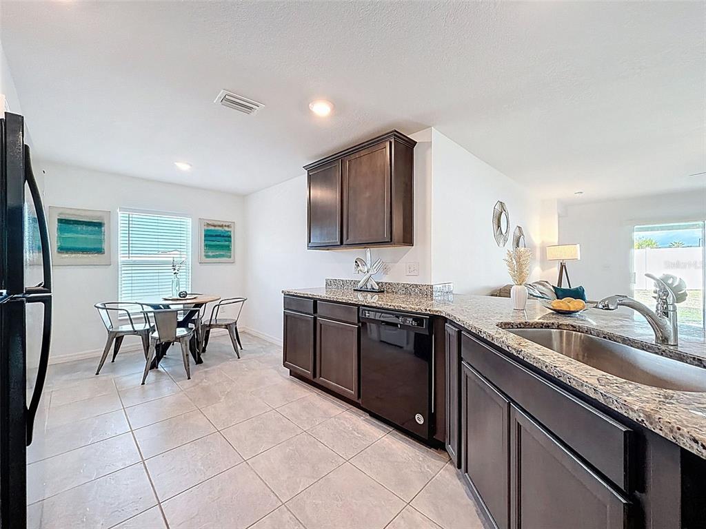 12943 Impatiens Street Spring Hill, FL 34609 - Photo 2 of 53 a kitchen with granite countertop a sink stove and cabinets