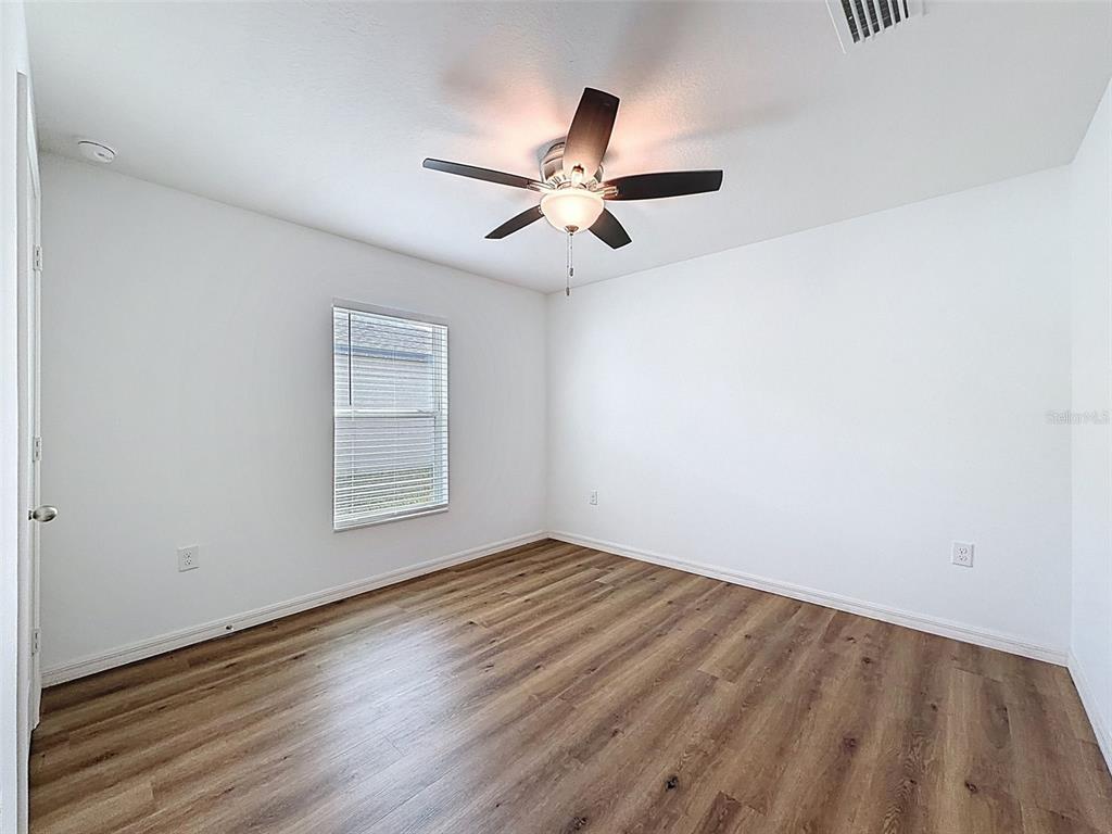 12943 Impatiens Street Spring Hill, FL 34609 - Photo 35 of 53 an empty room with wooden floor ceiling fan and windows