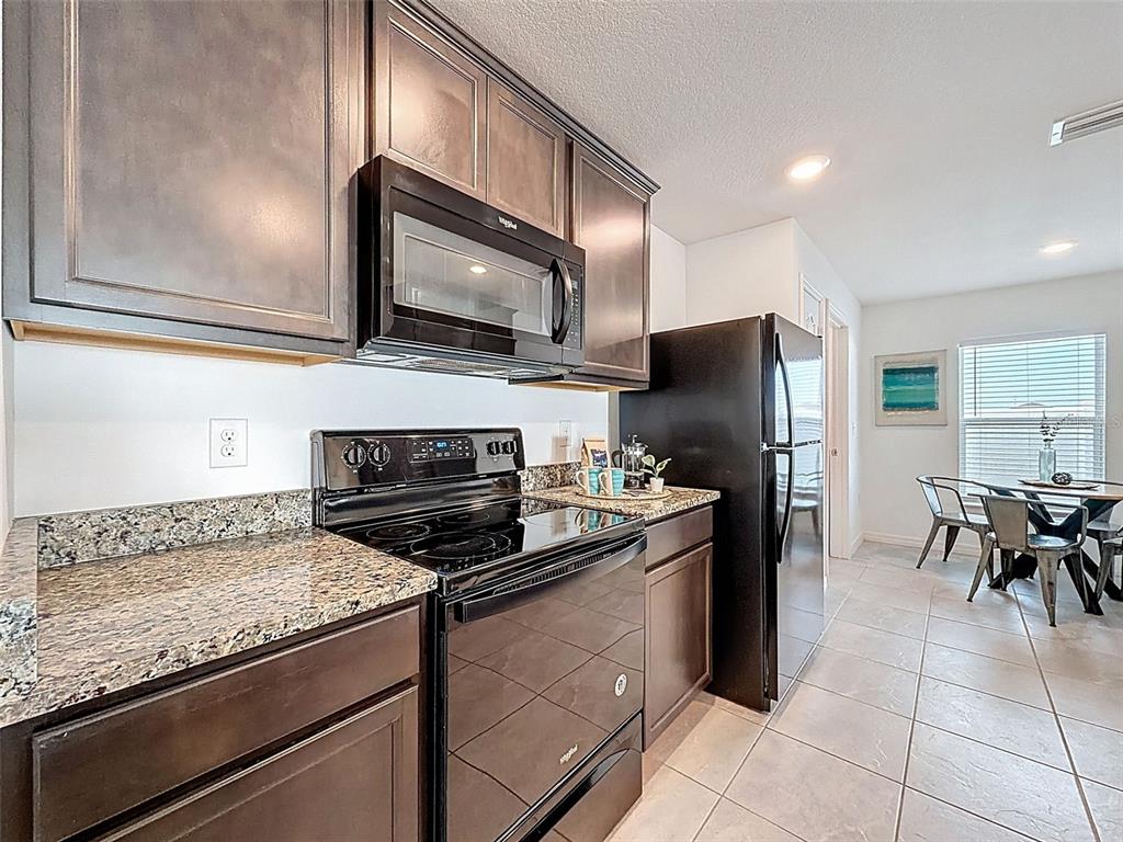 12943 Impatiens Street Spring Hill, FL 34609 - Photo 10 of 53 a kitchen with granite countertop stainless steel appliances and wooden cabinets