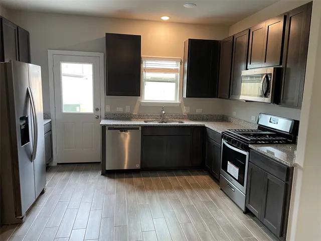 a kitchen with stainless steel appliances granite countertop a stove a sink and a refrigerator