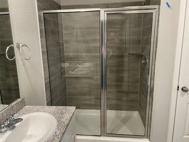 a bathroom with a granite countertop sink mirror and shower