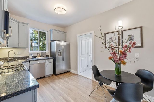 a kitchen with stainless steel appliances granite countertop a refrigerator a stove a sink dishwasher a dining table and chairs with wooden floor