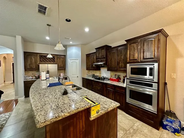 a kitchen with kitchen island granite countertop stainless steel appliances and stove top oven