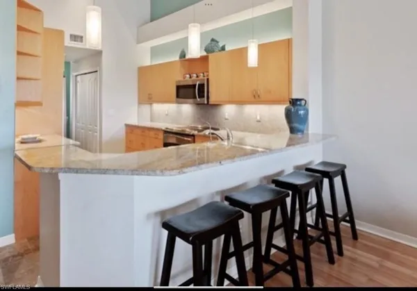 a kitchen with stainless steel appliances granite countertop a sink a stove a refrigerator cabinets and a dining table