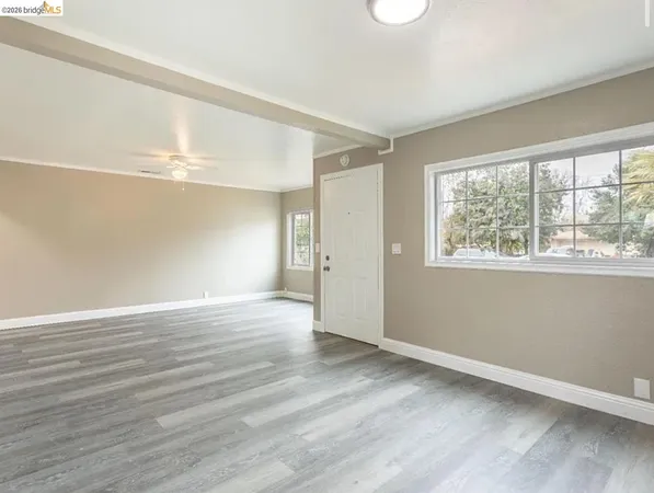 a view of an empty room with wooden floor and a window
