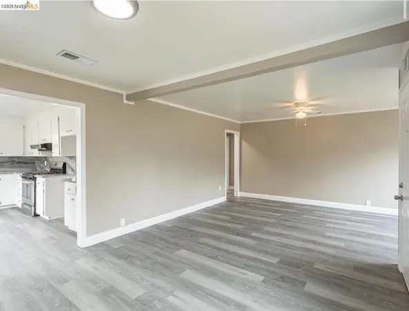 a view of an empty room with kitchen and a window