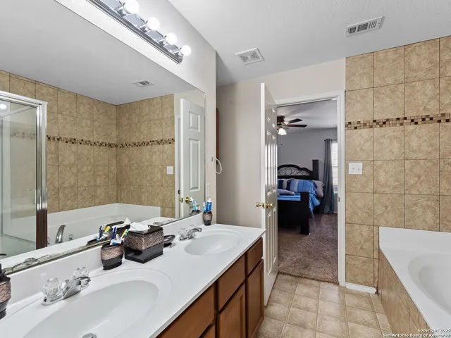 a en suite bathroom with a double vanity sink a mirror and a bathtub