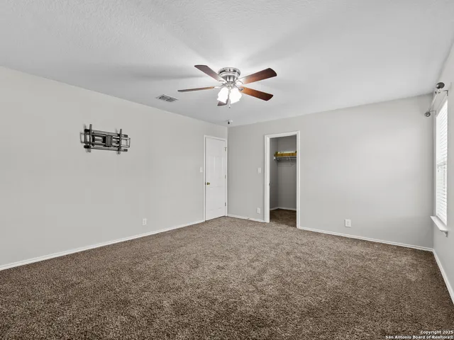 an empty room with closet and a ceiling fan