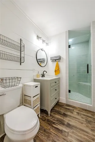 a bathroom with a toilet sink vanity granite and shower