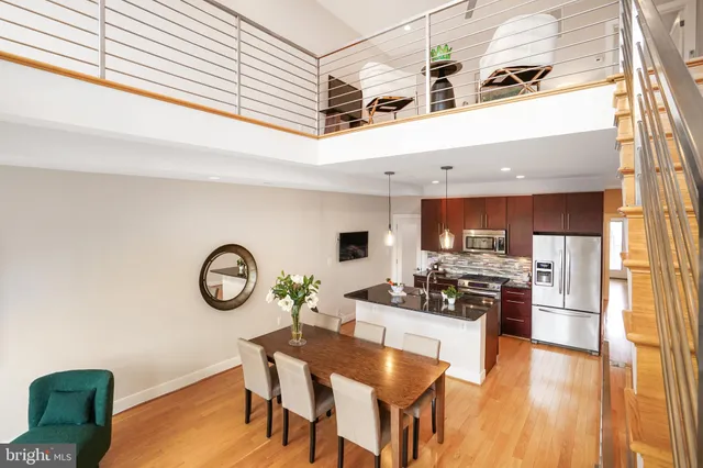 a kitchen with stainless steel appliances kitchen island granite countertop a stove a sink a dining table and chairs with wooden floor