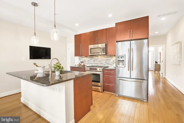 a kitchen with kitchen island a counter top space stainless steel appliances and wooden floor