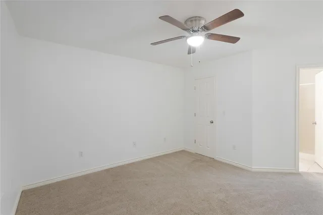 an empty room with a chandelier fan and windows