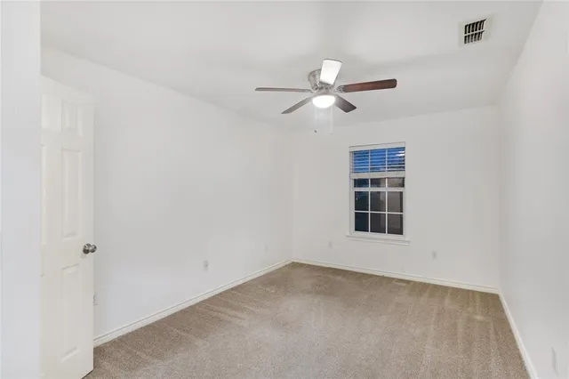an empty room with a window and ceiling fan