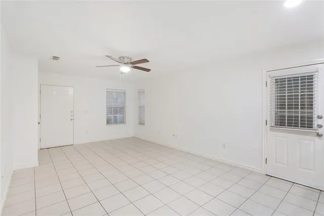an empty room with white walls and ceiling fan