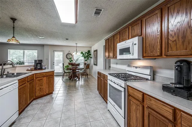a kitchen with stainless steel appliances granite countertop wooden cabinets a stove top oven a sink and dishwasher