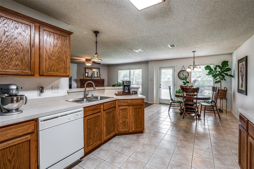8606 Scooner Street Rowlett, TX 75089 - Photo 7 of 30 a kitchen with a dining table chairs sink and cabinets
