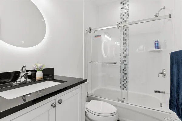 a bathroom with a granite countertop sink a toilet and shower