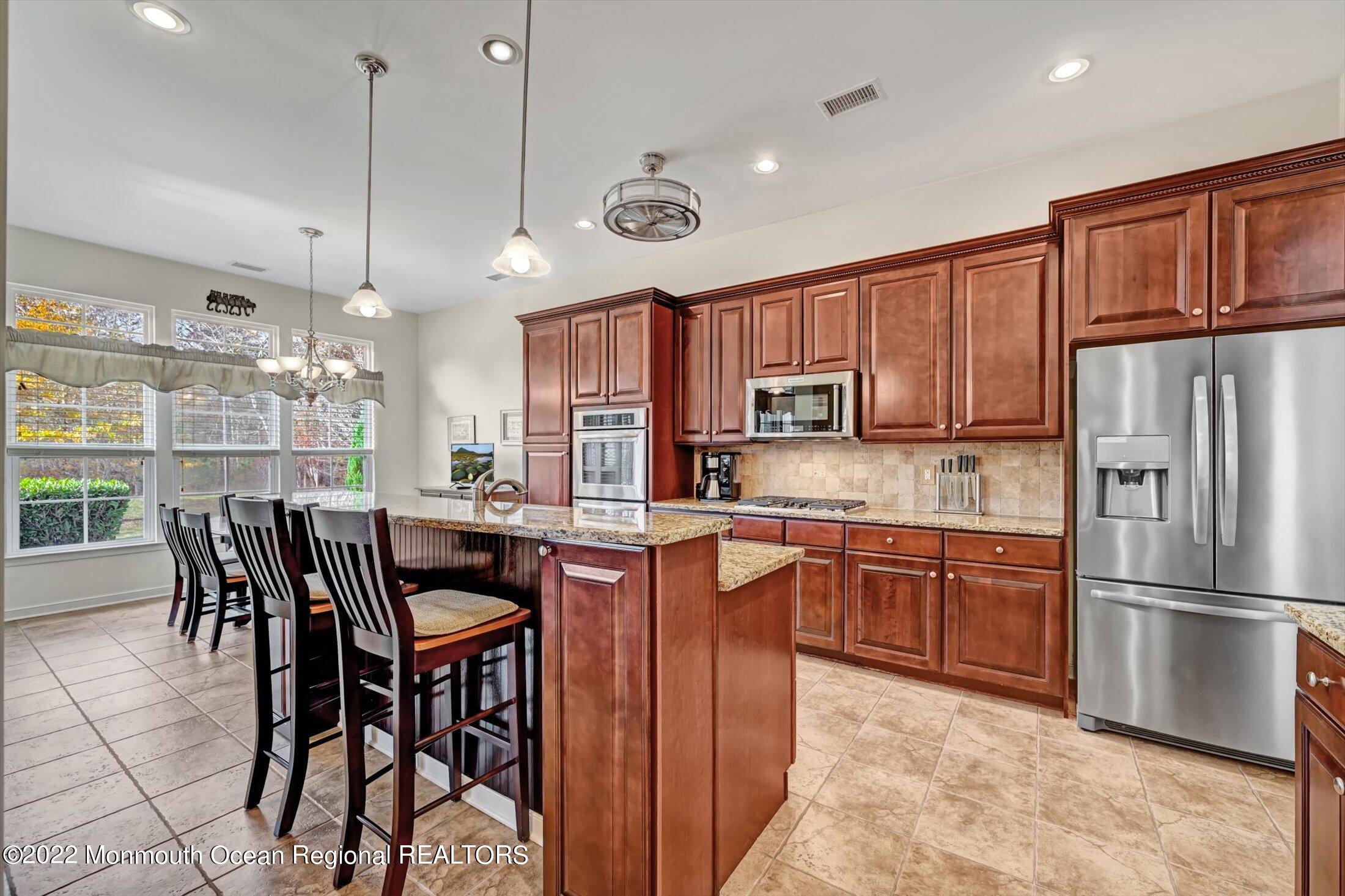 20 East Francesa Court Farmingdale, NJ 07727 - Photo 15 of 78 a kitchen with stainless steel appliances granite countertop a stove a refrigerator a kitchen island a dining table and chairs with wooden floor