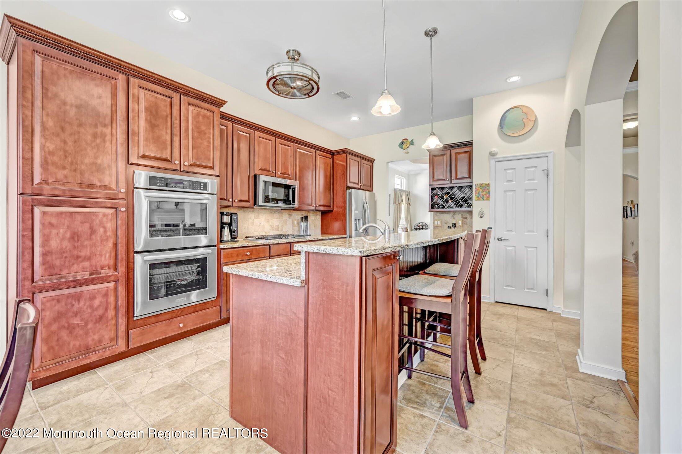 20 East Francesa Court Farmingdale, NJ 07727 - Photo 17 of 78 a kitchen with stainless steel appliances granite countertop a stove top oven a refrigerator and a dining table with wooden floor