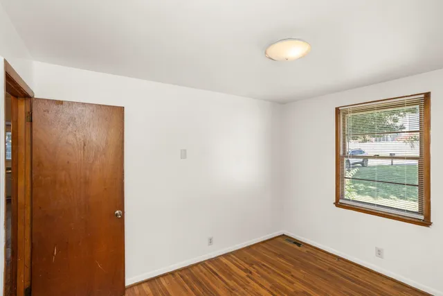 a view of an empty room with window and wooden floor
