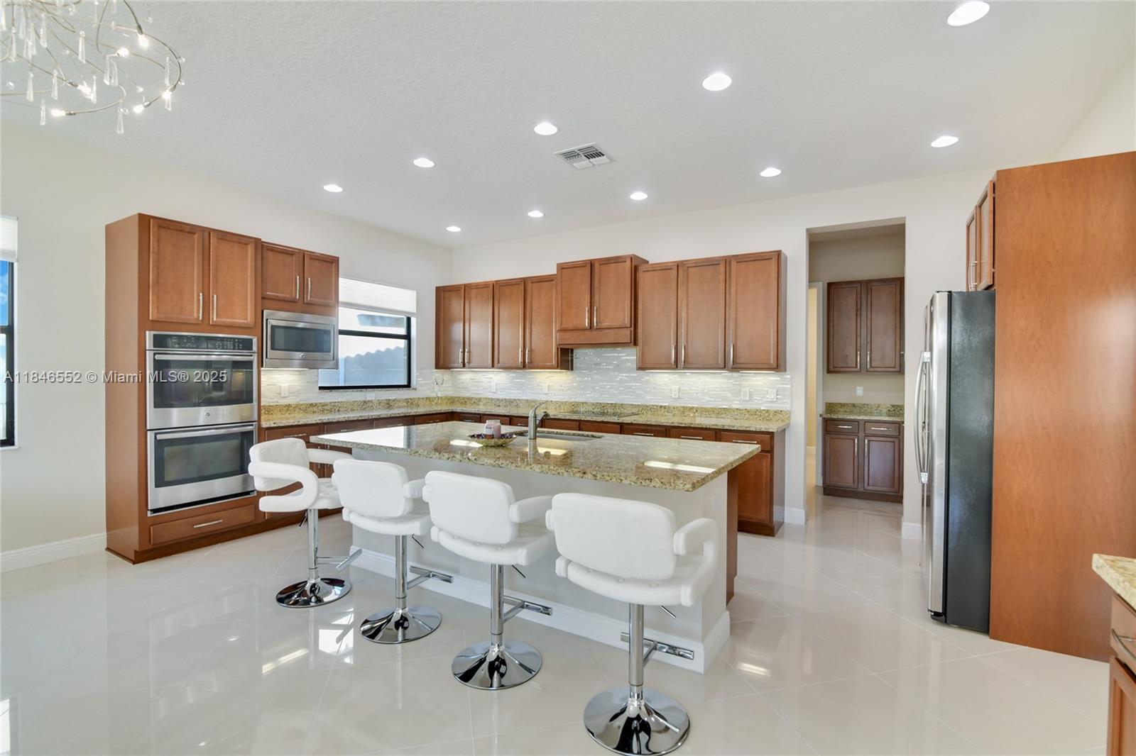 12137 Boca Reserve Lane Boca Raton, FL 33428 - Photo 3 of 35 a kitchen with a refrigerator a sink and chairs