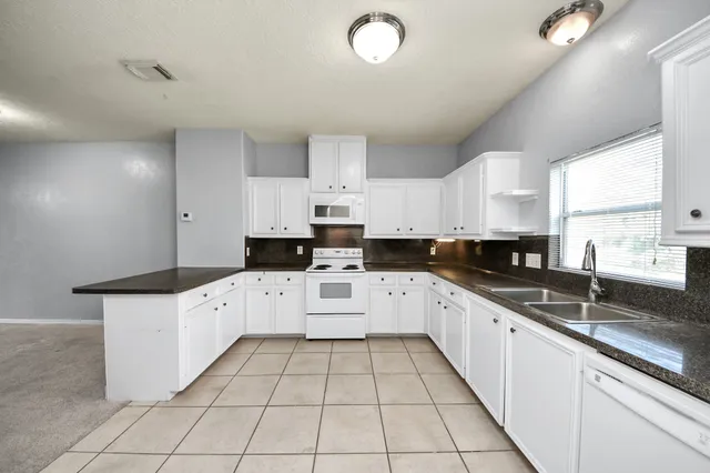 a kitchen with granite countertop white cabinets and white appliances