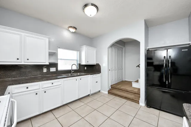 a large white kitchen with sink and stainless steel appliances