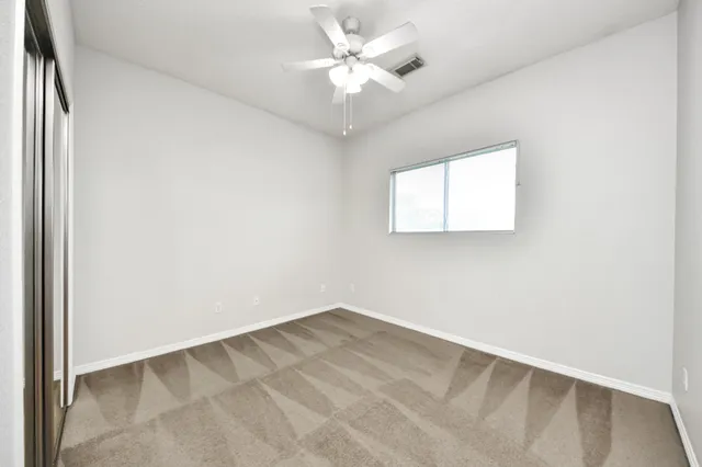 an empty room with windows and fan