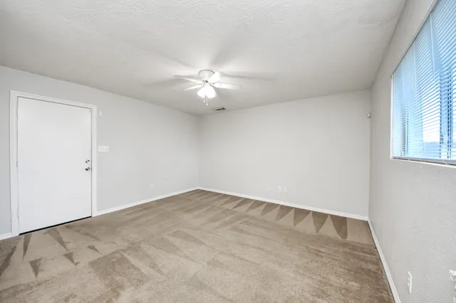 an empty room with windows and fan