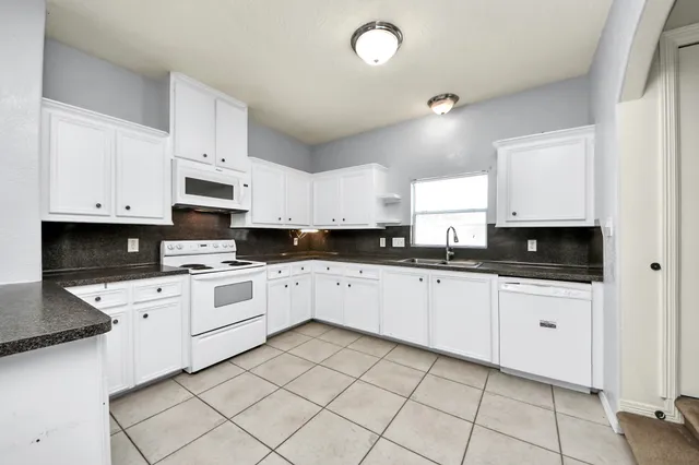 a kitchen with white cabinets appliances and a sink