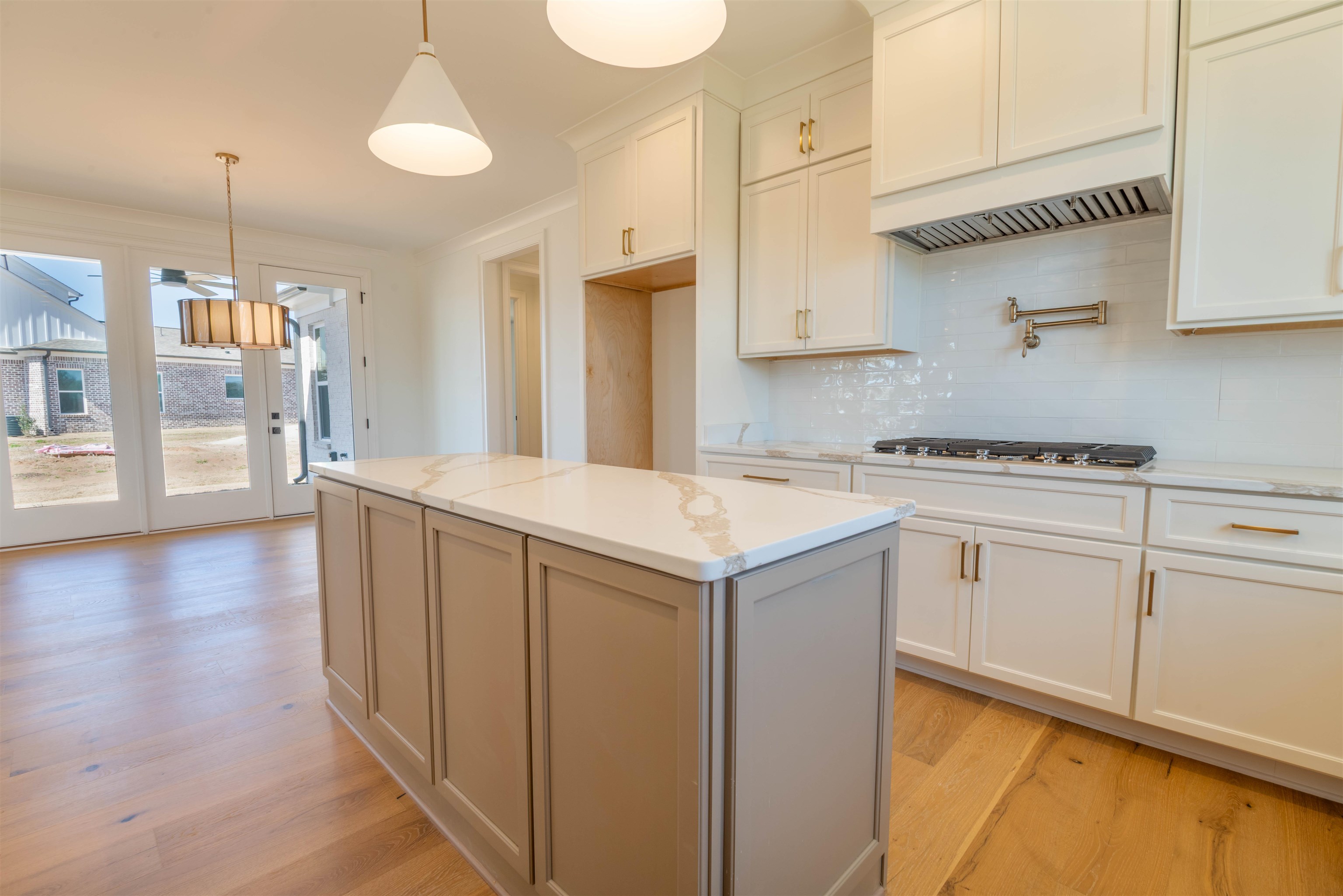 30 Rambling Rex Trail Piperton, TN 38017 - Photo 14 of 27 Kitchen with backsplash, a center island, decorative light fixtures, light wood-style floors, and stainless steel gas stovetop