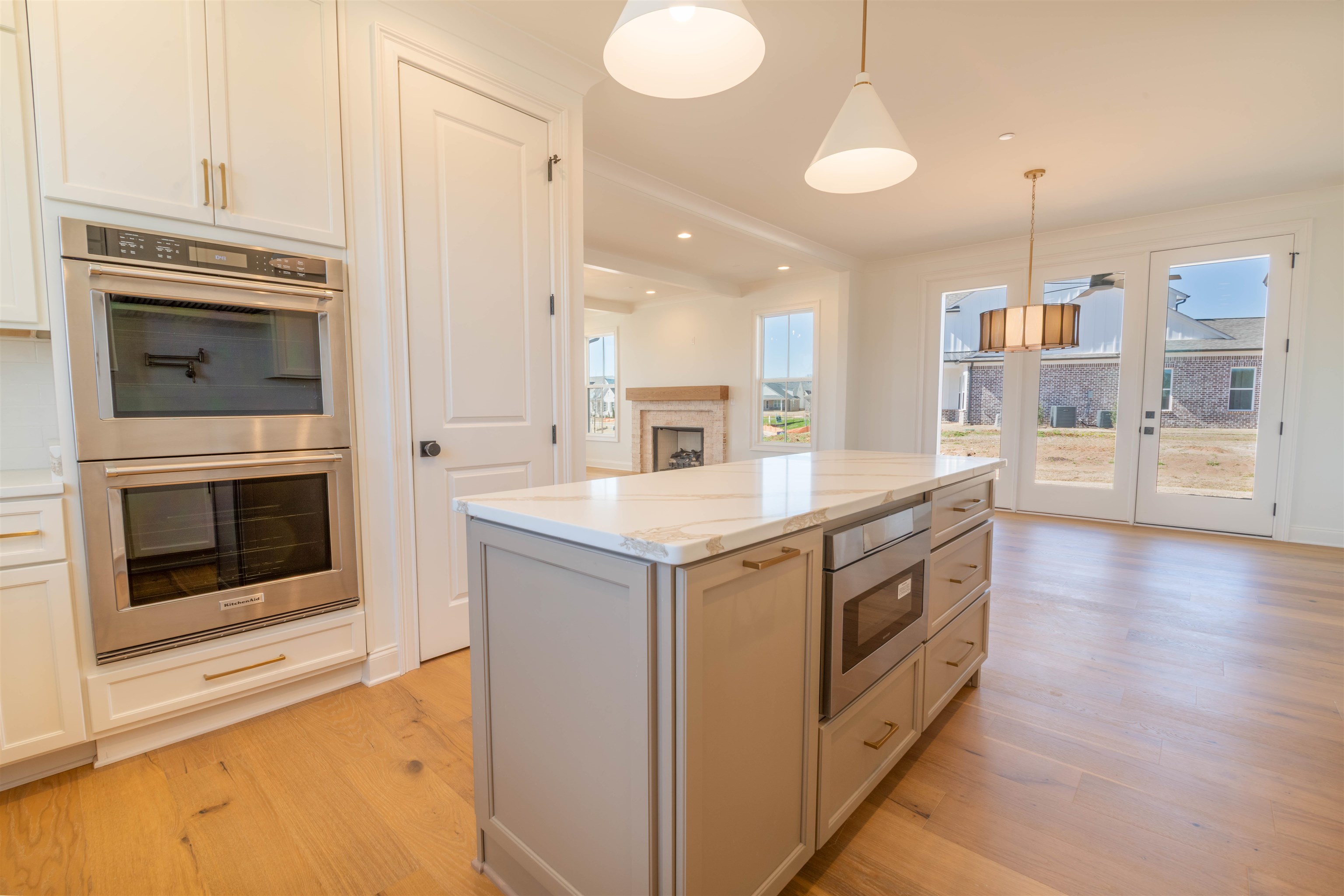 30 Rambling Rex Trail Piperton, TN 38017 - Photo 20 of 27 Kitchen with light stone counters, a kitchen island, appliances with stainless steel finishes, light wood finished floors, and hanging light fixtures