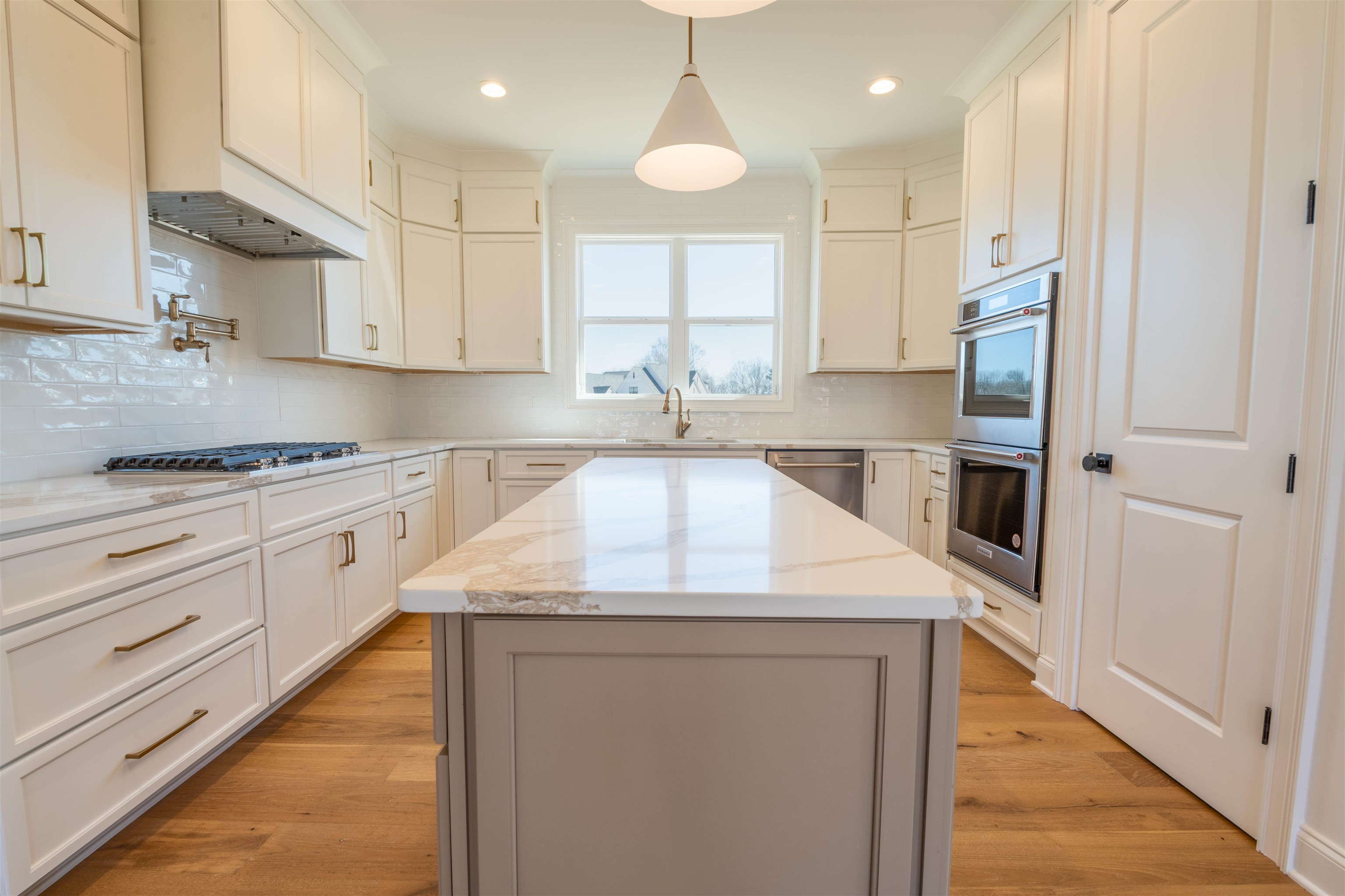 30 Rambling Rex Trail Piperton, TN 38017 - Photo 6 of 27 Kitchen featuring light stone counters, light wood-style flooring, a sink, appliances with stainless steel finishes, and tasteful backsplash