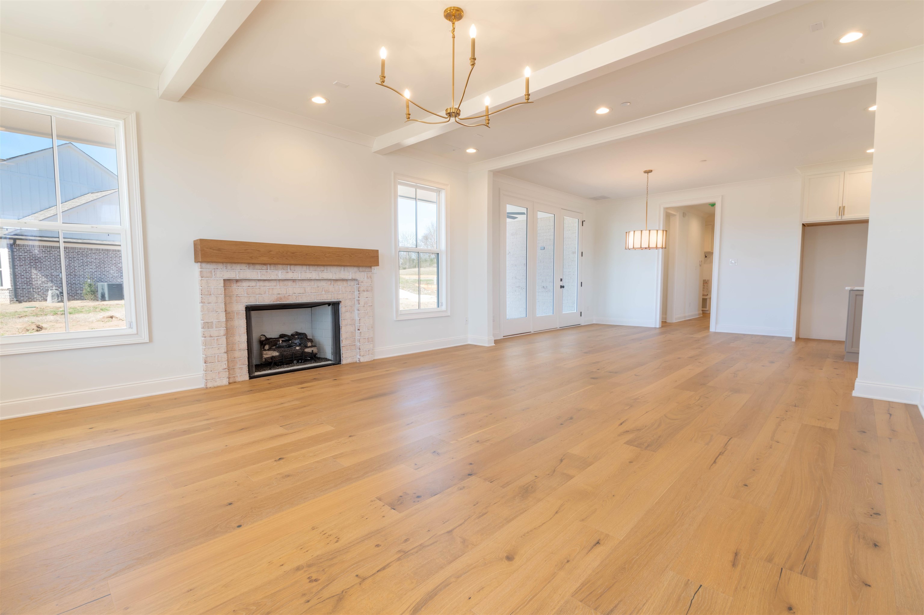 30 Rambling Rex Trail Piperton, TN 38017 - Photo 9 of 27 Unfurnished living room featuring a notable chandelier, beamed ceiling, light wood-type flooring, and baseboards