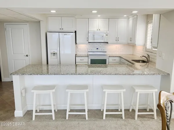 a kitchen with granite countertop white cabinets and refrigerator