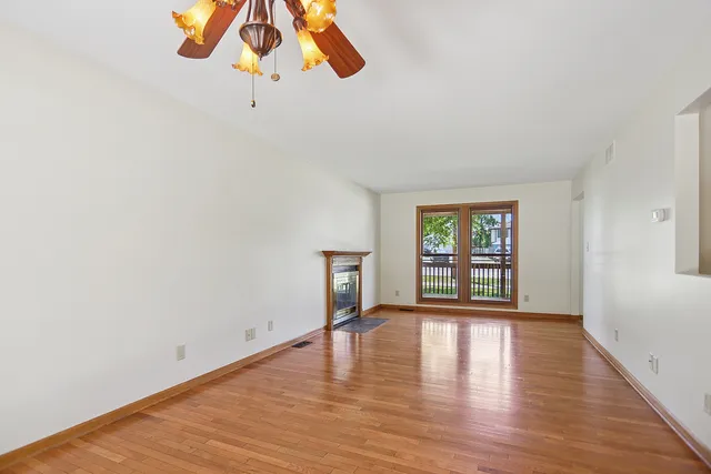 a view of an empty room with wooden floor and windows