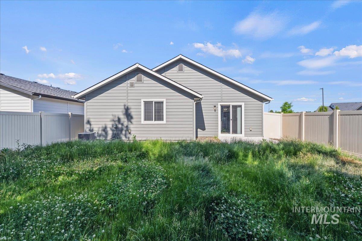 3091 S Green Boise, ID 83709 - Photo 25 of 27 Expansive backyard featuring a partial vinyl fence, a concrete patio, and a sliding glass door entry