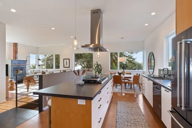a kitchen with stainless steel appliances a dining table chairs stove and cabinets