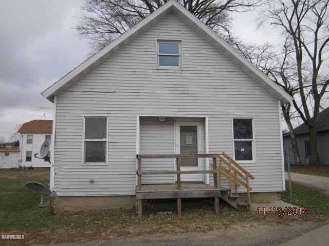 a view of a white house with a small yard and large tree