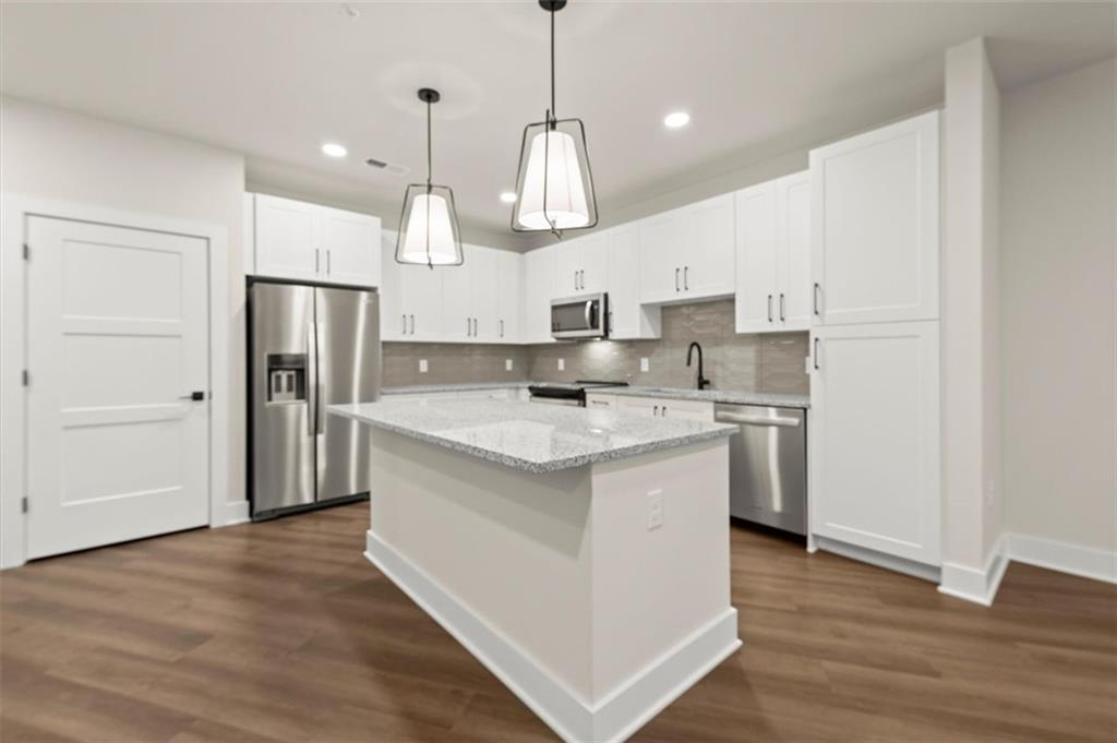 a kitchen with stainless steel appliances granite countertop a sink a stove a refrigerator and island with wooden floor