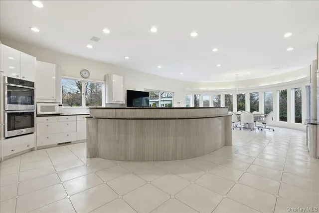 a large kitchen with stainless steel appliances lots of counter top space cabinets and furniture