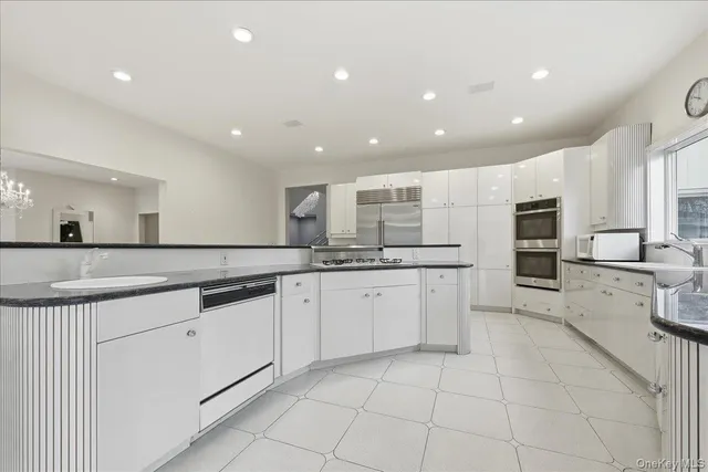 a large white kitchen with a sink and dishwasher a stove top oven with wooden floor